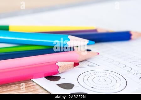 Colored pencils scattered on a school notebook. Close-up. Stock Photo