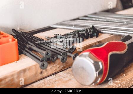 Tools for the job. Screws, nails and a screwdriver are on the table. Various carpentry tools. Stock Photo
