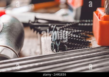 Tools for the job. Screws, nails and a screwdriver are on the table. Various carpentry tools. Stock Photo
