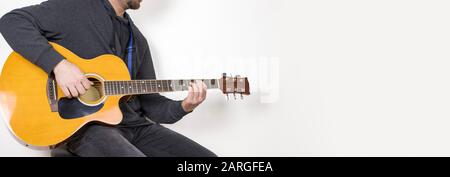 man playing acoustic guitar sitting on bar stool, musical instrument, isolated background Stock Photo