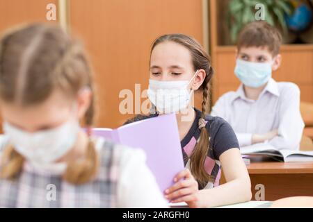 Pupils wearing protection mask to prevent virus during lesson in classroom in school Stock Photo