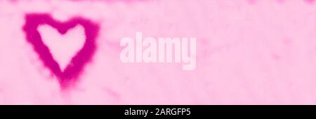 Painted pink heart made of spray paint on a pink wall. Valentines day concept. Banner. Stock Photo