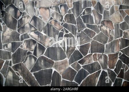 Natural slate stone wall of irregular polygons in gray brown colors Stock Photo