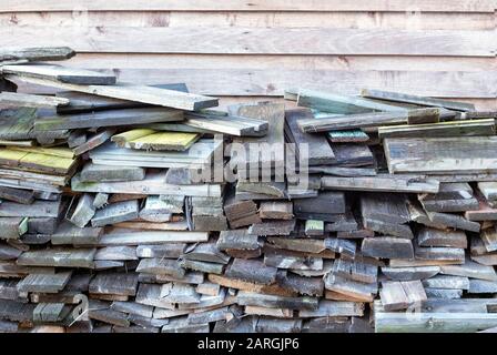 Many old weathered boards stacked against wooden wall Stock Photo