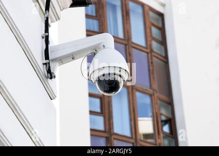 White and black spherical external surveillance camera on building facade Stock Photo