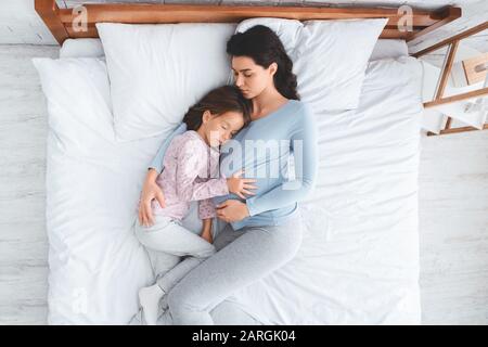 Peaceful image of expecting woman having nap with little daughter Stock Photo
