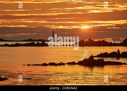 looking WSW from St Agnes towards the Bishop Rock Lighthouse on the Isles of Scilly at sunset Stock Photo