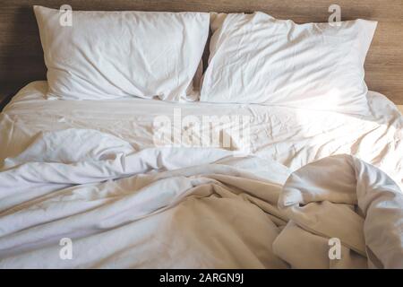 messy comfy white bed sheets and pillow life on Holiday . untidy unmade bed with white crumpled bed sheet and two messy pillows in a hotel room. Holid Stock Photo