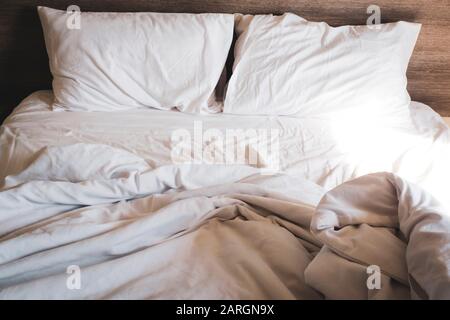 messy comfy white bed sheets and pillow life on Holiday . untidy unmade bed with white crumpled bed sheet and two messy pillows in a hotel room. Holid Stock Photo