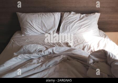messy comfy white bed sheets and pillow life on Holiday . untidy unmade bed with white crumpled bed sheet and two messy pillows in a hotel room. Holid Stock Photo