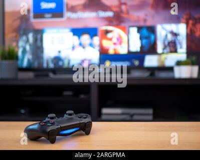 UK, Jan 2020: Sony dualshock 4 controller remote for Playstation 4 with tv screen in background