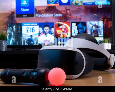UK, Jan 2020: Playstation VR headset and move controller for gaming and virtual reality with tv screen behind