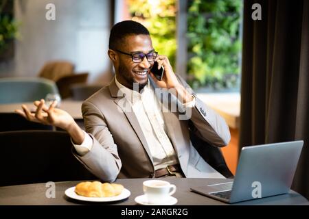 Black guy talking on phone sitting at the table Stock Photo