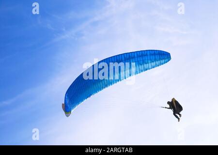 One skydiver on blue paraglider in blue sky Stock Photo