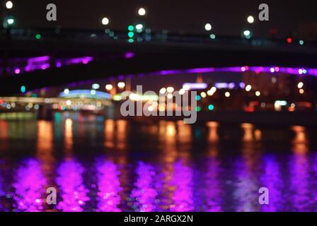 Blurred night cityscape with multi-colored lights and river bridges of Moscow. Stock Photo