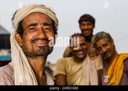 A portrait of a cycle rickshaw driver, waiting for customers, three friends in the distance Stock Photo