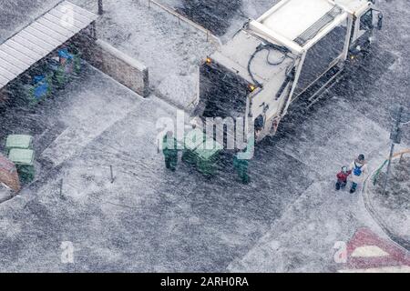 Garbage men in snow storm working in residential area Stock Photo