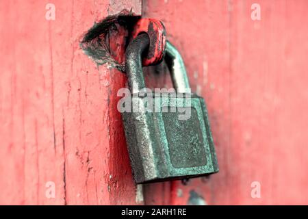 Old rusty cast iron padlock on red painted door Stock Photo