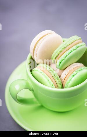 Homemade french macaroons or macarons. Green cup with cookies. Mint cookies with vanilla cream on a gray background, copy space Stock Photo