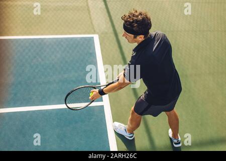 Top view of a young tennis player with racket ready to serve a tennis ball. Professional player standing at the baseline holding the tennis racket and Stock Photo