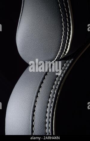 Stitched leather upholstery on a  car seat. Dark grey luxury leather covering to car interior. Stock Photo