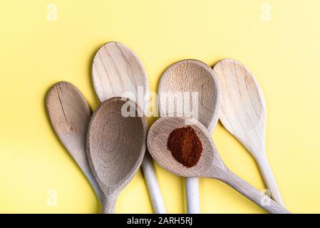 Group of old wooden spoons isolated on a pale cream background. One with some paprika. Stock Photo