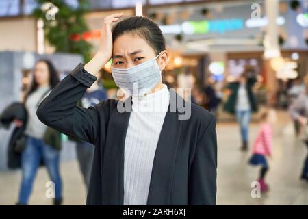 Alarmed female wears medical mask to protect Stock Photo