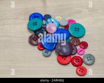 buttons of different shapes and colors on neutral wooden background Stock Photo