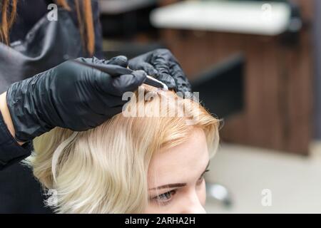 Hairdresser coloring woman's hair in the salon, close up. Stock Photo