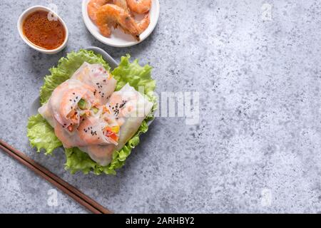 Spring rolls with prawn, noodles and vegetables in rice paper on grey stone background. Close up. Asian cuisine. Stock Photo