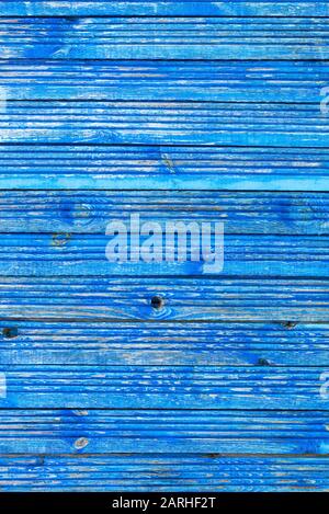 Parallel wooden old planks are painted with blue weathered and peeling paint classic light blue color, vertical image with texture of old wood. Stock Photo