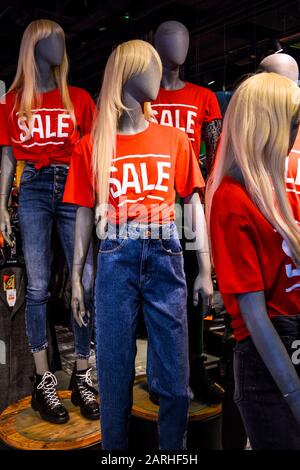 Mannequins in a window of a clothing store in T-Shirts With Signs Advertising Sale Stock Photo