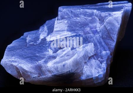 Close up macro photograph of a fluorite mineral glowing blue under ultraviolet light Stock Photo
