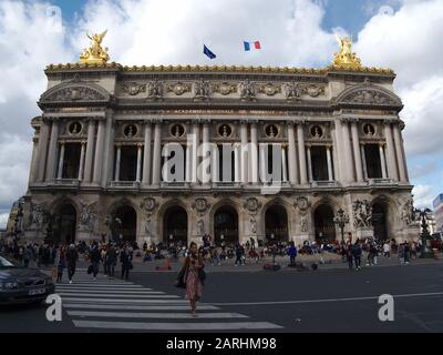 The crowd at the Opera Garnier and a woman crossing the street while cars are waiting. Stock Photo