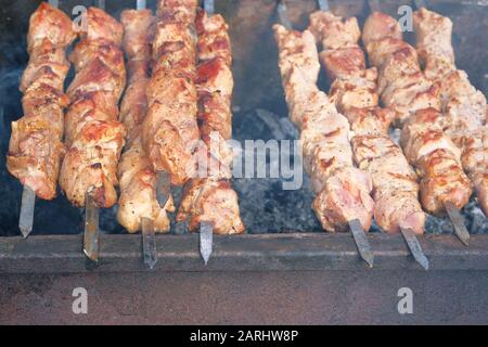 BBQ outdoor during summer time. Shish kebab national cuisine of Central Asia and middle East. Festival outdoor. Cooking meat on barbecue. Stock Photo