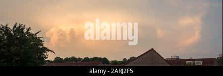 Panorama of a storm cloud (Cumulonimbus) at dusk, illuminated by the setting sun Stock Photo