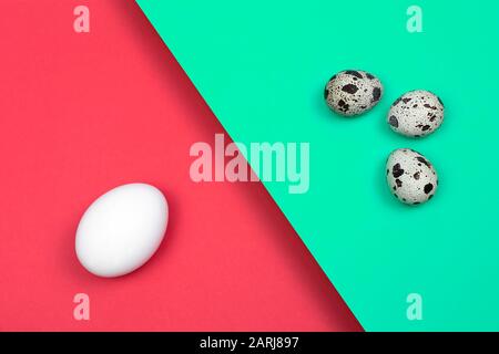 Beautiful spotted fresh quail and chicken eggs on a green blue and red paper background. raw food, narural food Stock Photo