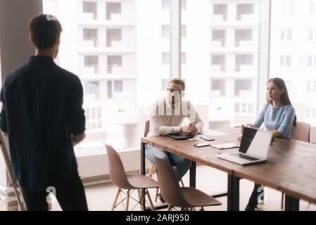 Businessman doing presentation, using whiteboard, explaining to colleagues Stock Photo