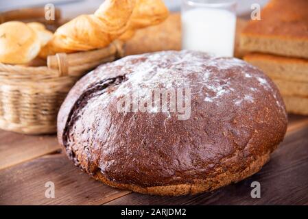 Traditional dark homemade bread with other types of bakery products, top view on a dark wooden table Stock Photo