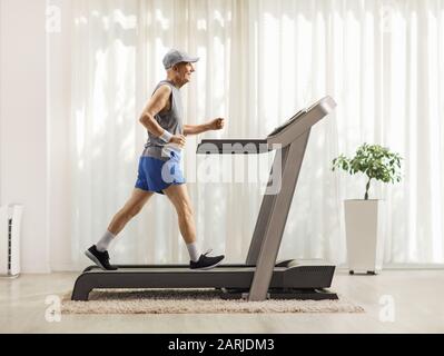 Full length profile shot of an active senior man on a treadmill in a luxurious home Stock Photo