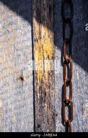 Pattern of old weathered timbered wall with an old rusty chain Stock Photo