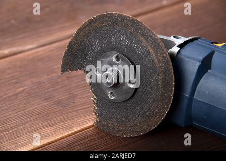 A grinder with a broken blade on a wooden table. The danger of using power tools Stock Photo