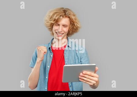 Young man using tablet computer and rejoiced Stock Photo