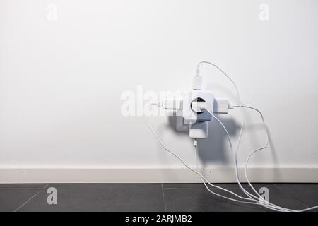 Modern power socket with four cables plugged to it. Stock Photo