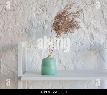 Wheat bouquet in green ceramic vase on white background. Minimal floral composition. Minimal floral composition Stock Photo