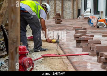 construction worker drawing a line in the sand with a pickaxe Stock Photo
