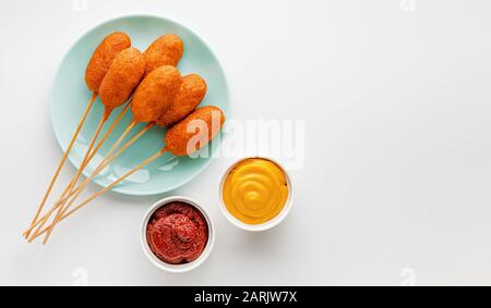 Heap of deep fried corn dogs on white background. Top view, copy space. Stock Photo
