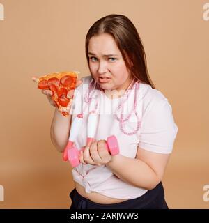 Woman struggling to lose weight on beige background Stock Photo