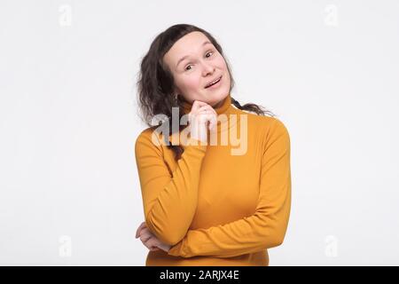 Portrait of pensive young woman in yellow clothes looking up, over white background Stock Photo