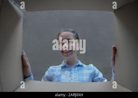 Happy woman opening cardboard box with gift and looking inside - holiday concept Stock Photo